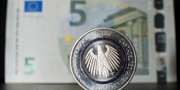 Illustration taken on April 14, 2016 in Hanover, central Germany, shows a five-euro collector coin titled 'Planet Earth' in front of a five-euro banknote.From now on, the coin is available at branches of the Deutsche Bundesbank (German Central Bank) and many other banks. As the Bundesbank explains on its internet site, 'The coin consists of three components an outer ring depicting the cosmos, with numerous planets; an inner core portraying Earth; and a blue polymer ring holding both metal components together. The polymer ring, which shines blue when held up to the light, visually represents the link between Earth and the cosmos'. / AFP / dpa / Julian Stratenschulte / Germany OUT (Photo credit should read JULIAN STRATENSCHULTE/AFP/Getty Images)