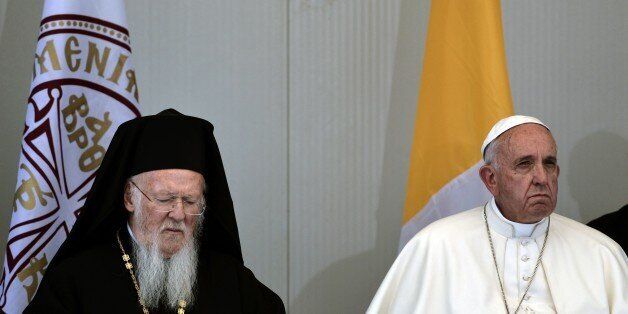 Patriarch Bartholomew (L) sits next to Pope Francis during their visit at the Moria detention center in Mytilene on April 16, 2016.Twelve Syrian refugees were accompanying Pope Francis on his return flight to Rome after his visit to Lesbos on Saturday and will be housed in the Vatican, the Holy See said. / AFP / ARIS MESSINIS (Photo credit should read ARIS MESSINIS/AFP/Getty Images)