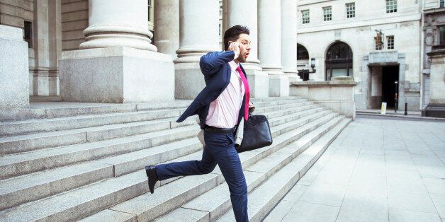 Businessman on cell phone running on city staircase