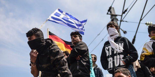 Refugees and migrants hold German and Greece flags as they protest to reopen the border near their makeshift camp in the northern border village of Idomeni, on April 11, 2016. Fresh protests broke out as Greece and Macedonia blamed each other for an incident in which tear gas and rubber bullets were fired on migrants trying to breach the closed border to get to western Europe on April 10. Medical charity Doctors Without Borders (MSF) said 260 people were treated for injuries after the flare-up on the Greece-Macedonia border. / AFP / BULENT KILIC (Photo credit should read BULENT KILIC/AFP/Getty Images)