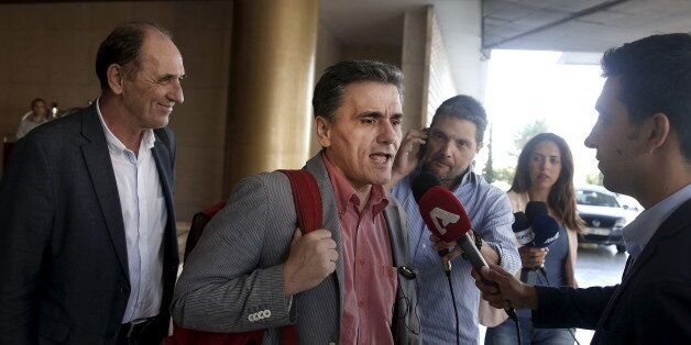 Greek Finance Minister Euclid Tsakalotos (C) speaks to the media while Economy Minister George Stathakis (L) looks on as they leave a hotel following an overnight meeting with representatives of the International Monetary Fund, the European Commission, the European Central Bank and the eurozone's rescue fund, the European Stability Mechanism in Athens, August 11, 2015. Greece and its international lenders clinched a multi-billion-euro bailout agreement on Tuesday after marathon talks through the