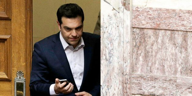 Greece's Prime Minister Alexis Tsipras uses his mobile phone during an emergency Parliament session for the governmentâs proposed referendum in Athens, Saturday, June 27, 2015. Greece's place in the euro currency bloc looked increasingly shaky on Saturday, when eurozone countries rejected a monthlong extension to its bailout program and the prime minister called for a risky popular vote on the country's financial future. (AP Photo/Petros Karadjias)