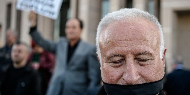A demonstrator with his mouth covered, stands outside the Istanbul courthouse on April 1, 2016, where Turkish opposition Cumhuriyet daily's editor-in-chief Can Dundar and Ankara bureau chief Erdem Gul attend their trial.Cumhuriyet daily's editor-in-chief Can Dundar and Ankara bureau chief Erdem Gul face possible life terms on spying charges over a news report accusing President Recep Tayyip Erdogan's government of seeking to illicitly deliver arms bound for neighbouring Syria. / AFP / OZAN KOSE (Photo credit should read OZAN KOSE/AFP/Getty Images)