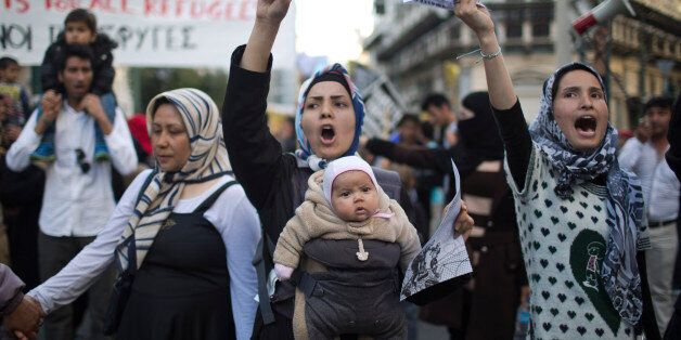 A woman with a baby chants slogans during a protest in central Athens, on Wednesday, March 30, 2016. Some 1,500 stranded migrants and refugees, joined by Greek supporters, marched to the European Commission building in central Athens Wednesday to protest a migration agreement between the European Union and Turkey that is due to take full effect Monday.(AP Photo/Petros Giannakouris)