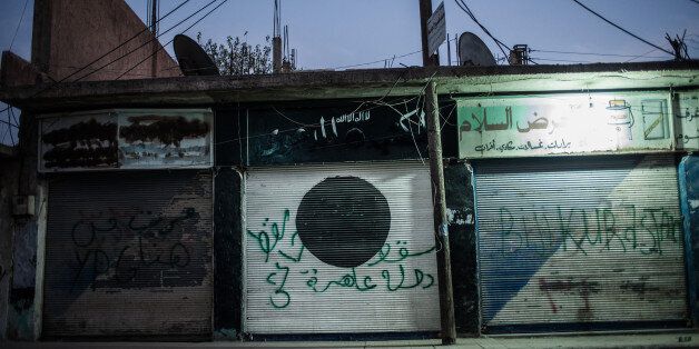TEL ABYAD, OCTOBER 15: Graffiti on the door of a shuttered store formerly selling ISIS-approved products reads 'ISIS fell, the whore state fell.' Next door, graffiti reads 'Long-live Kurdistan.'