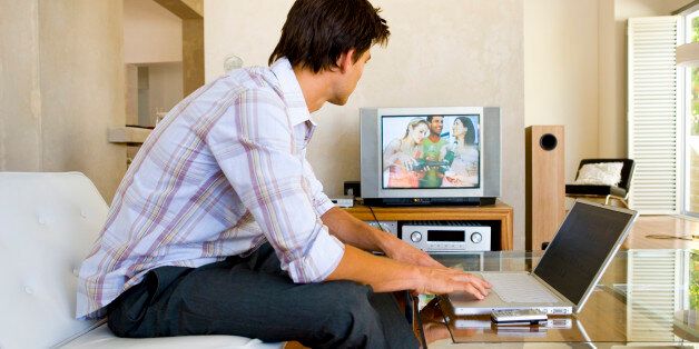 Man watching television with laptop