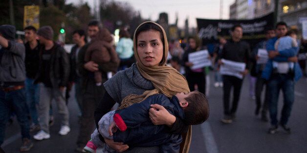 A woman carries her baby during a protest in central Athens, on Wednesday, March 30, 2016. Some 1,500 stranded migrants and refugees, joined by Greek supporters, marched to the European Commission building in central Athens Wednesday to protest a migration agreement between the European Union and Turkey that is due to take full effect Monday. (AP Photo/Petros Giannakouris)