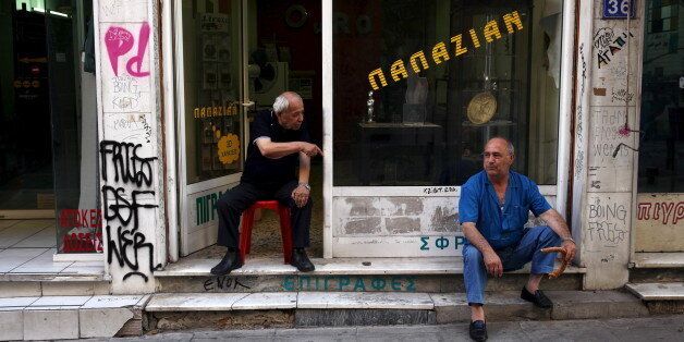 Men sit in front of a shop in central Athens, Greece, July 21, 2015. The Greek government submitted legislation to parliament on Tuesday required by its international lenders to start talks on a multi-billion euro rescue package. Prime Minister Alexis Tsipras has until Wednesday night to get those measures adopted in the assembly. A first set of reforms triggered a rebellion in his party last week and passed only thanks to votes from pro-EU opposition parties. REUTERS/Yiannis Kourtoglou