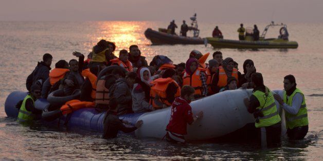 Volunteers help migrants and refugees on a dingy as they arrive on the shore of the northeastern Greek island of Lesbos, after crossing the Aegean sea from Turkey on Sunday, March 20, 2016. In another incident two Syrian refugees have been found dead on a boat on the first day of the implementation of an agreement between the EU and Turkey on handling the new arrivals. (AP Photo/Petros Giannakouris)