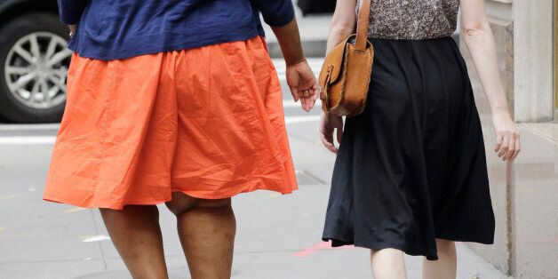 An obese woman, left, walks in New York, Monday, July 13, 2015. (AP Photo/Mark Lennihan)