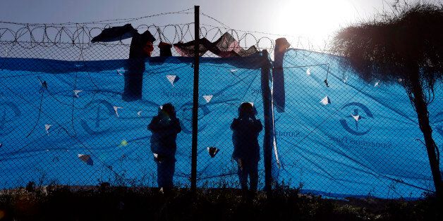Children look out behind a wire fence of a refugee camp in the western Athens' suburb of Schisto, Monday, April 4, 2016, during the first day of the implementation of the deal between EU and Turkey. Under the deal, migrants arriving illegally in Greece will be returned to Turkey if they do not apply for asylum or if they make an asylum claim that is rejected. (AP Photo/Lefteris Pitarakis)