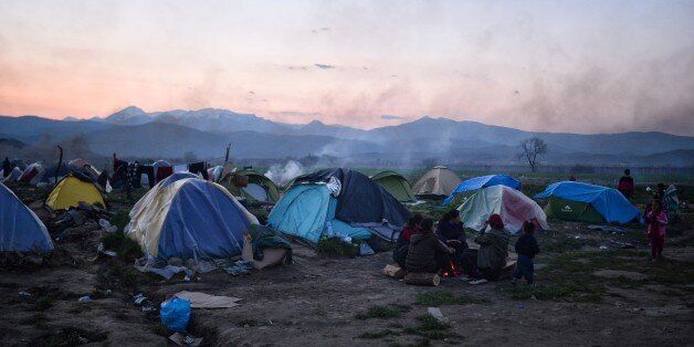 People sit by their tents in the makeshift camp at the Greek-Macedonian borders near the village of Idomeni on March 20, 2016. Flimsy boats packed with migrants continued to land in Greece from Turkey on March 20, 2016 despite the start of a landmark deal between the European Union and Ankara to stem the massive influx. Under the controversial deal, which came into force at midnight, all migrants landing on the Greek islands face being sent back to Turkey. / AFP / LOUISA GOULIAMAKI (Ph