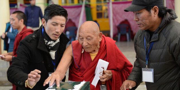 Former political prisoner 85-year-old Tibetan Palden Gyatso (C) is guided as he casts his vote to elect a Sikyong (Prime Minister) of the Central Tibetan Administration and members of the parliament in McLeod Ganj on 20 March 2016. Tens of thousands of exiled Tibetans have voted for a new leader tasked with sustaining their struggle for greater autonomy in their Chinese-ruled homeland as the Dalai Lama retreats from the political frontline. / AFP / Lobsang Wangyal (Photo credit should read LOBSANG WANGYAL/AFP/Getty Images)
