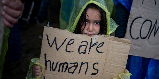 A girl holds a placard during a protest held by migrants and refugees to call for the reopening of the borders at a makeshift camp at the Greek-Macedonian border near the village of Idomeni on March 23, 2016. The UN refugee agency harshly criticized an EU-Turkey deal on curbing the influx of migrants to Greece, saying reception centers had become 'detention facilities', and suspended some activities in the country. The EU and Ankara struck a deal aiming to cut off the sea crossing from Turkey to the Greek islands that enabled 850,000 people to pour into Europe last year, many of them fleeing the brutal war in Syria. / AFP / ANDREJ ISAKOVIC (Photo credit should read ANDREJ ISAKOVIC/AFP/Getty Images)
