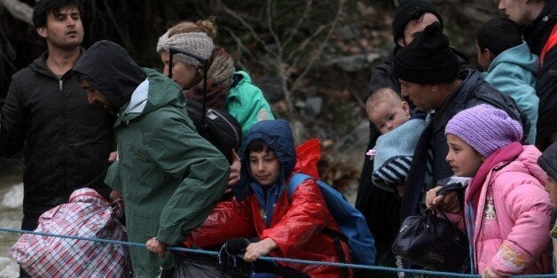 Migrants and refugees cross a river on their way to Macedonia from a makeshift camp at the Greek-Macedonian border near the Greek village of Idomeni where thousands of them are stranded by the Balkan border blockade on March 14, 2016. Hundreds of desperate migrants were stopped by Macedonian troops after wading thigh-deep through a surging river to cross the border from Greece, where thousands have been left stranded after Balkan states slammed Europe's migrant door shut. / AFP / SAKIS MITROLIDIS (Photo credit should read SAKIS MITROLIDIS/AFP/Getty Images)