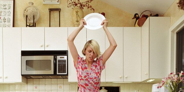 Woman smashing plates in kitchen