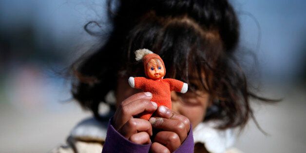 A migrant girl shows her doll in the makeshift refugee camp at the northern Greek border point of Idomeni, Greece, Saturday, March 26, 2016. Greece's border with Macedonia has been shut to refugees since earlier this month after a string of countries shut down the route which migrants used to go from Greece to central and northern Europe. Those stranded in the camp and surrounding fields have been living in dire conditions in small tents pitched in muddy fields. (AP Photo/Darko Vojinovic)