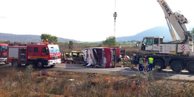 Emergency services personnel stand at the scene of a bus accident crashed on the AP7 highway that links Spain with France along the Mediterranean coast near Freginals halfway between Valencia and Barcelona early Sunday, Spain, March 20, 2016. The bus was reportedly hired out to carry students to and from a fireworks festival in Valencia and was on the return leg of its journey when the accident happened. (AP Photo)