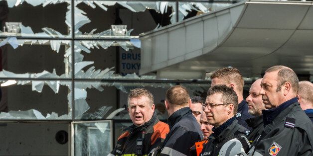 Firefighters and first responders stand next to blown out windows at Zaventem Airport in Brussels on Wednesday, March 23, 2016. Belgian authorities were searching Wednesday for a top suspect in the country's deadliest attacks in decades, as the European Union's capital awoke under guard and with limited public transport after scores were killed and injured in bombings on the Brussels airport and a subway station. (AP Photo/Geert Vanden Wijngaert, Pool)