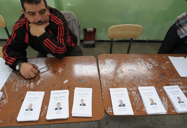 An electoral worker waits for voters to cast their ballots at a polling station in Algiers as part of...