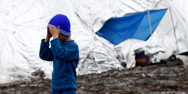 A migrant boy fixes his woolen hat in an improvised camp on the border line between Macedonia and Serbia near the northern Macedonian village of Tabanovce, Friday, March 11, 2016. About 1,500 refugees remain stranded at the Macedonian border with Serbia as the borders on the Balkan migrant route are closing. (AP Photo/Darko Vojinovic)