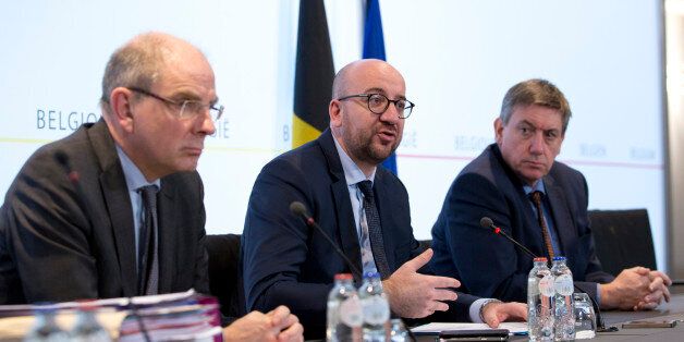 Belgian Prime Minister Charles Michel, center, addresses a media conference in Brussels on Wednesday, March 16, 2016. Belgian investigators were hunting Wednesday for two suspects who fled an apartment linked to the Nov. 13 attacks in Paris, after a police sniper killed a third man and uncovered weapons, ammunition and an Islamic State flag, officials said Wednesday. At left is Belgian Justice Minister Koen Geens and right is Belgian Interior Minister Jan Jambon. (AP Photo/Virginia Mayo)