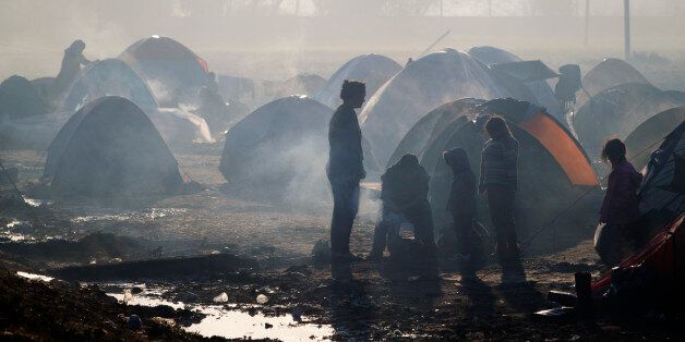 Migrants try to start a fire at the northern Greek border point of Idomeni, Greece, Saturday, March 19, 2016. German Chancellor Angela Merkel is urging migrants in the squalid tent city at Idomeni, on the Greek-Macedonian border, to trust Greek authorities and leave for better accommodation as thousands have stayed on site after the closure of Macedonia's border, clinging to hopes the Balkan route used for months by migrants heading for central Europe will reopen.(AP Photo/Vadim Ghirda)