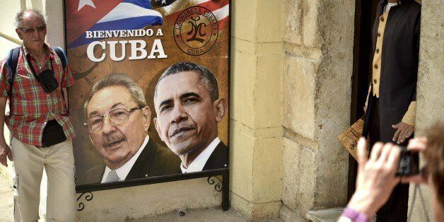 A tourist poses for a picture with a sign placed at the entrance of a restaurant with the images of Cuban and US Presidents Raul Castro and Barack Obama in Havana, Cuba on March 19, 2016. Political and economic reforms in Cuba will be a no-go area during talks between Cuban leader Raul Castro and US President Barack Obama, Cuban Foreign Minister Bruno Rodriguez said in Havana Thursday. On Sunday, Obama will become the first sitting US president to visit Cuba since 1928, capping his historic policy of ending a bitter standoff that has endured since Fidel Castro's overthrow of the US-backed government of Fulgencio Batista in 1959. AFP PHOTO/ Yuri CORTEZ / AFP / YURI CORTEZ (Photo credit should read YURI CORTEZ/AFP/Getty Images)