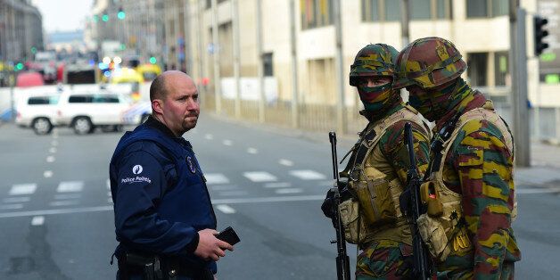 Policemen and soldier stand guard at the entrance of a security perimeter set near Maalbeek metro station, on March 22, 2016 in Brussels, after a blast at this station near the EU institutions caused deaths and injuries. AFP PHOTO / EMMANUEL DUNAND / AFP / EMMANUEL DUNAND (Photo credit should read EMMANUEL DUNAND/AFP/Getty Images)