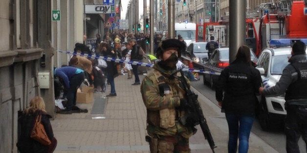 In this image taken from TV an armed member of the security forces stands guard as emergency services attend the scene after a explosion in a main metro station in Brussels on Tuesday, March 22, 2016. Explosions rocked the Brussels airport and the subway system Tuesday, killing a number of people and injuring many others just days after the main suspect in the November Paris attacks was arrested in the city, police said. (AP Photo)