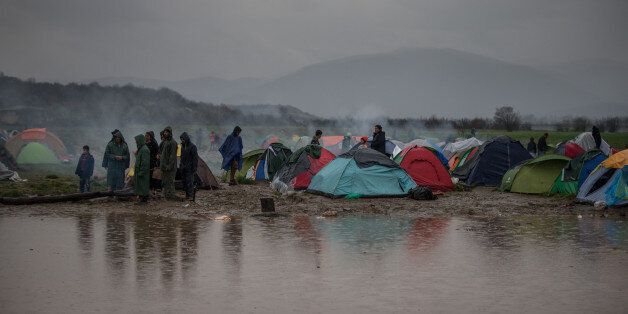 IDOMENI, GREECE - MARCH 13: People stand beside tents close to standing water that has developed due to heavy rain fall at the Idomeni refugee camp on the Greek Macedonia border on March 13, 2016 in Idomeni, Greece. The decision by Macedonia to close its border to migrants last Wednesday has left thousands of people stranded at the Greek transit camp. The closure, following the lead taken by neighbouring countries, has effectively sealed the so-called western Balkan route, the main migration ro