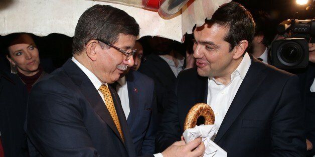 IZMIR, TURKEY - MARCH 08: Turkish Prime Minister Ahmet Davutoglu (L) offers a traditional Turkish bagel (simit) to Greek Prime Minister Alexis Tsipras (R) as they walk at Konak district after the Fourth Meeting of High Level Cooperation Council in Izmir, Turkey on March 08, 2016. (Photo by Turkish Prime Ministry / Mustafa Aktas/Anadolu Agency/Getty Images)