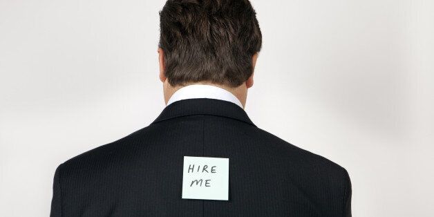 Man wearing a suit with 'hire me' note on his back