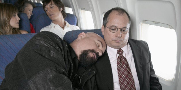 Businessman Sitting in an Aeroplane Trapped by a Man Sleeping by His Side