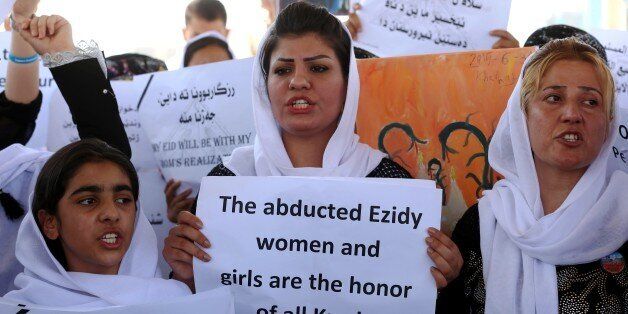 Iraqi Yazidi women hold placards during a protest outside the United Nations (UN) office in the Iraqi city of Arbil, the capital of the autonomous Kurdish region, on August 2, 2015 in support of women from their community who were kidnapped last year in the Sinjar region by the Islamic State (IS) group jihadists. In 2014, the jihadists massacred Yazidis, forced tens of thousands of them to flee, captured thousands of girls and women as spoils of war and used them as sex slaves. AFP PHOTO / SAFIN HAMED (Photo credit should read SAFIN HAMED/AFP/Getty Images)