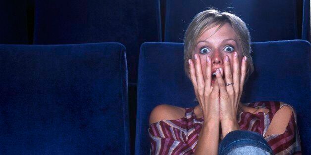 Blond woman in movie theater viewing horror film