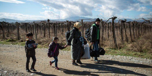 A migrant family crosses the Greek-Macedonian border near the town of Gevgelija, on February 14, 2016. Dutch Foreign minister Bert Koenders on February 14, 2016 spent an hour in a Vinojug recipient center near Gevgelija talking with migrants, children, UNICEF and Red Cross representatives, police and others members who are taking care of migrants heading to the EU from devastated homes in Syria, Afghanistan and Iraq. / AFP / Robert ATANASOVSKI (Photo credit should read ROBERT ATANASOVSKI/AFP/Getty Images)
