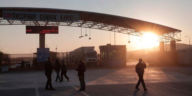 People walk at the closed Turkish border crossing with Syria in the outskirts of the town of Kilis, in southeastern Turkey, Monday, Feb. 8, 2016. Turkey for its part was under pressure from the EU to open its border to up to 35,000 Syrians who have massed along the frontier in the past few days fleeing an onslaught by government forces in Aleppo. (AP Photo/Lefteris Pitarakis)