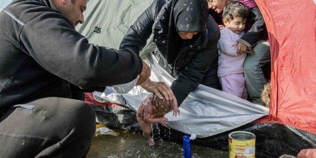 IDOMENI, GREECE - MARCH 6: Refugees wash a new born baby as they stay in tents that they set up in the Idomeni town in Greece, near the Macedonian border on March 6, 2016. (Photo by Iker Pastor/Anadolu Agency/Getty Images)