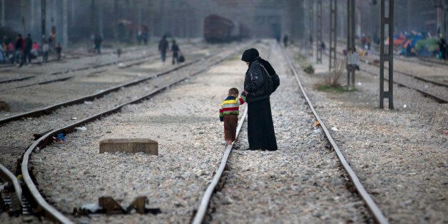A woman holds the hand of a toddler walking on a railway track at the northern Greek border station of Idomeni, Monday, March 7, 2016. Greek police officials say Macedonian authorities have imposed further restrictions on refugees trying to cross the border, saying only those from cities they consider to be at war can enter as up to 14,000 people are trapped in Idomeni, while another 6,000-7,000 are being housed in refugee camps around the region.(AP Photo/Vadim Ghirda)