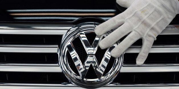 FILE - In this Oct. 23, 2015 file photo a worker touches the logo of Volkswagen AG on a Phaeton in Dresden, Germany. Volkswagen is reporting a loss of 1.67 billion euros (US dollar 1.83 billion) in the third quarter, Wednesday, Oct. 28, 2015, as earnings took a hit from 6.7 billion euros in set-asides for recalls and fines connected to cars rigged to evade U.S. diesel emissions testing. (Ralf Hirschberger/dpa via AP, file)