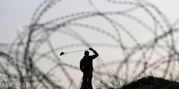 A Palestinian protester uses a slingshot during clashes with Israeli security forces on March 11, 2016, following a demonstration in solidarity with Palestinian prisoners held in Israeli jails, outside the compound of the Israeli-run Ofer prison near Betunia in the occupied West Bank. / AFP / ABBAS MOMANI (Photo credit should read ABBAS MOMANI/AFP/Getty Images)