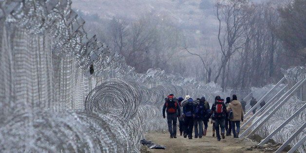 Refugees and migrants, who entered Macedonia from Greece illegally, walk between the two lines of the protective fence along the border line, near southern Macedonia's town of Gevgelija, Monday, Feb. 29, 2016. Macedonia is restricting the entry of refugees to match the number of those leaving the country, allowing in only refugees from Syria and Iraq, in response to bottlenecks further up along the Balkans migrant route. (AP Photo/Boris Grdanoski)