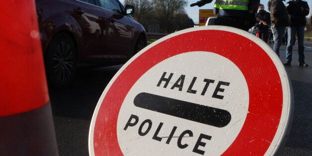 A French police officer monitors slows down the traffic at the border between France and Belgium in Neuville-en-Ferrain, northern France, Monday, Nov. 23, 2015. Belgian police launched more raids in Brussels and beyond early Monday, detaining five more people as they continued their hunt for a fugitive suspect in the Paris attacks. (AP Photo/Michel Spingler)