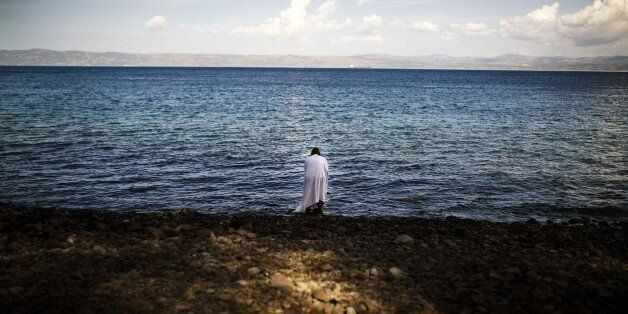 A woman stands on the beach, shortly after she arrived on the Greek island of Lesbos after crossing the Aegean sea from Turkey on October 12, 2015. Greece was hit by a huge new surge in migrants as the United Nations on October 9 approved a European seize-and-destroy military operation against people smugglers in the Mediterranean. AFP PHOTO / DIMITAR DILKOFF (Photo credit should read DIMITAR DILKOFF/AFP/Getty Images)
