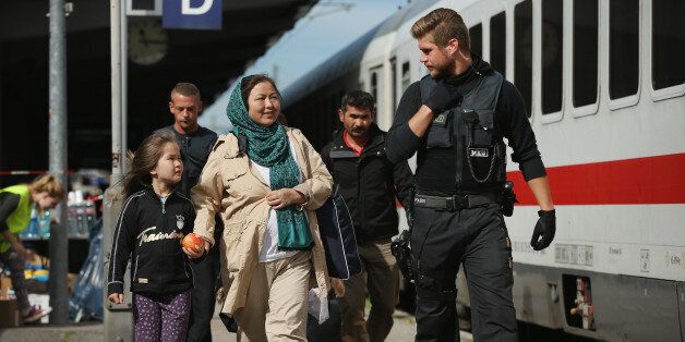 FREILASSING, GERMANY - SEPTEMBER 16: A German policeman escorts a family from Afghanistan, who had arrived with migrants on a regular train from Vienna, Austria, and told to disembark by German police, to board a government-chartered train for the German state of North Rhine-Westphalia on September 16, 2015 in Freilassing, Germany. German authorities have temporarily reinstated border controls along Germany's border to Austria and are using Freilassing as a hub for managing migrants arriving by train from Austria and the Balkans. Germany is still accepting up to thousands of new migrants daily but has imposed border controls in order to crack down on smugglers and to better regulate the flow of arriving migrants, tens of thousands of whom arrived in Germany over the last few weeks. Meanwhile Hungary has sealed it new fence along its border to Serbia and is ferrying remaining migrants to izs border with Austria. (Photo by Sean Gallup/Getty Images)