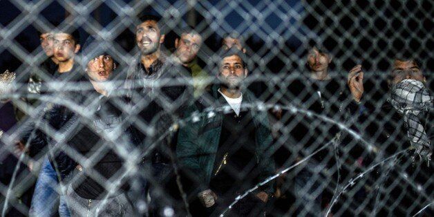 A photo taken from the Macedonian side of the border shows migrants from Afghanistan protesting behind a fence at the Greek-Macedonian border, near Gevgelija, on February 22, 2016, against Macedonia's refusal to allow Afghans to pass the border.Greece said on February 22 that it was taking action to persuade Macedonia to take in Afghan migrants as thousands remained stranded at the border and the main port in Athens. About 5,000 refugees and migrants are stuck at the border with Macedonia after the neighbouring non-EU state on February 21 refused to allow passage to Afghans, police said. / AFP / Robert ATANASOVSKI (Photo credit should read ROBERT ATANASOVSKI/AFP/Getty Images)