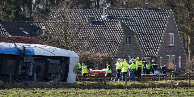 Emergency services carry a stretcher towards the wreck of a commuter train near Dalfsen, Netherlands, Tuesday, Feb. 23, 2016. A commuter train derailed after slamming into a crane which was crossing the tracks early Tuesday in the eastern Netherlands, killing one person and injuring six others, local emergency services said. The accident left the train's four carriages lying on their sides on or near the rails outside the town of Dalfsen, 125 kilometers (78 miles) east of Amsterdam. (AP Photo/Peter Dejong)