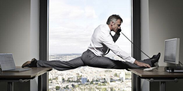 Flexible businessman balancing between two desks