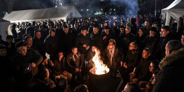 Opposition party supporters keep warm by a fire as they gather in front of Kosovo's government building in Pristina on February 24, 2016, to demand the resignation of the government, during the latest eruption in a long-running protest against agreements made with Serbia. / AFP / ARMEND NIMANI (Photo credit should read ARMEND NIMANI/AFP/Getty Images)